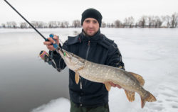 Winter fishing with spinning. Fisherman with pike fish trophy